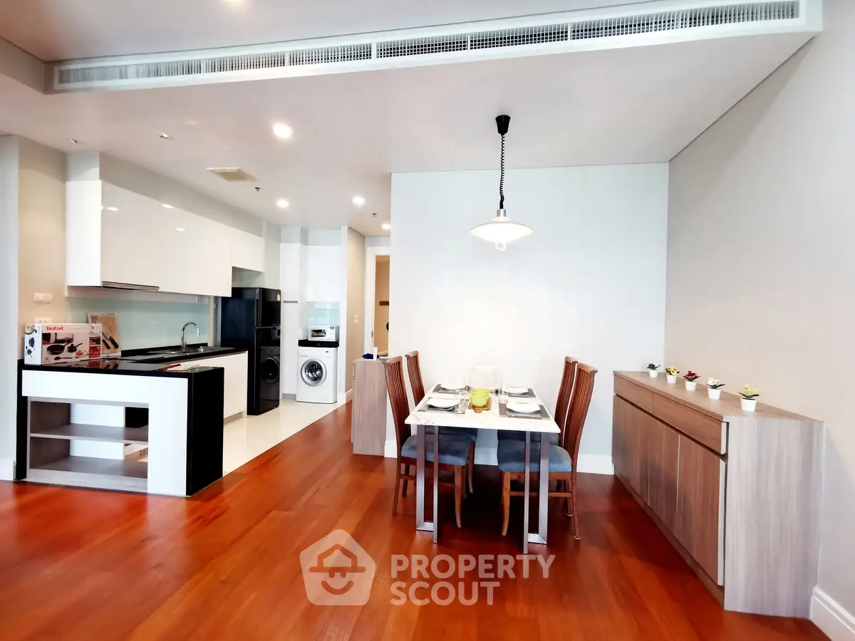 Modern open-layout kitchen and dining area with sleek design and wooden flooring.