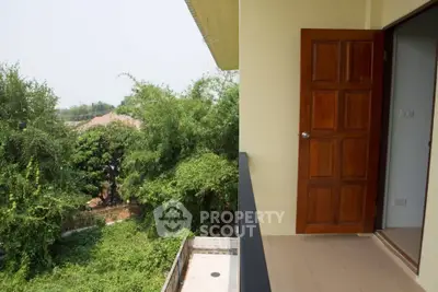 Spacious balcony with lush green view and wooden door entry