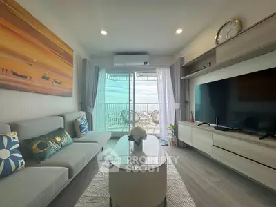 Modern living room with balcony view, stylish decor, and large TV in a cozy apartment.