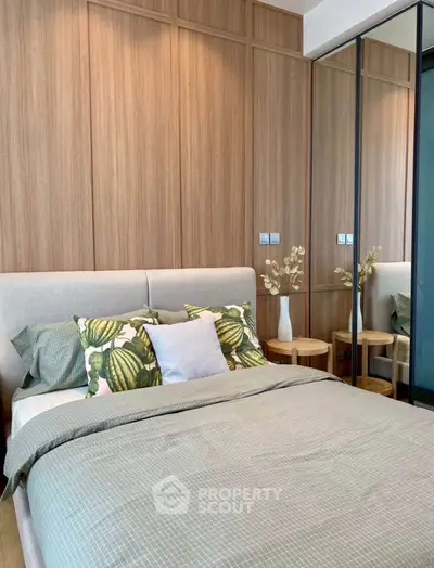 Modern bedroom with stylish decor and mirrored wardrobe in a cozy apartment.
