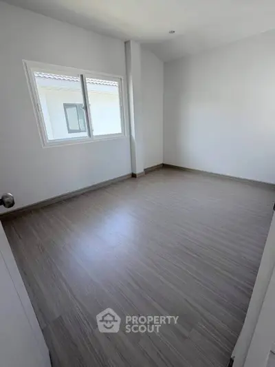 Spacious empty bedroom with large window and modern flooring