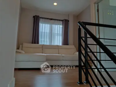 Cozy living room with elegant white sofa and modern railing, perfect for relaxation.