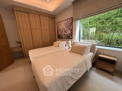 Elegant bedroom with twin beds, large window, and wooden wardrobe, offering a serene garden view.