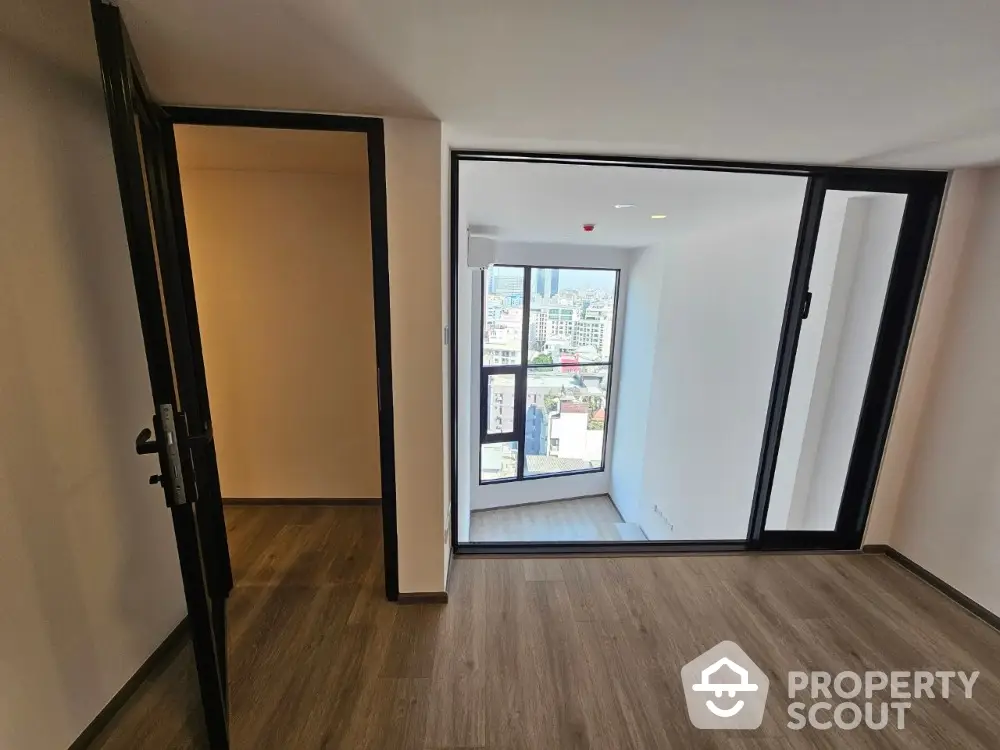 Spacious and bright corner unit with large windows offering a panoramic city view, modern flooring, and a versatile open layout.