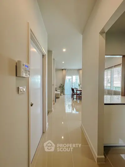 Modern hallway leading to a bright living room with elegant decor and dining area.