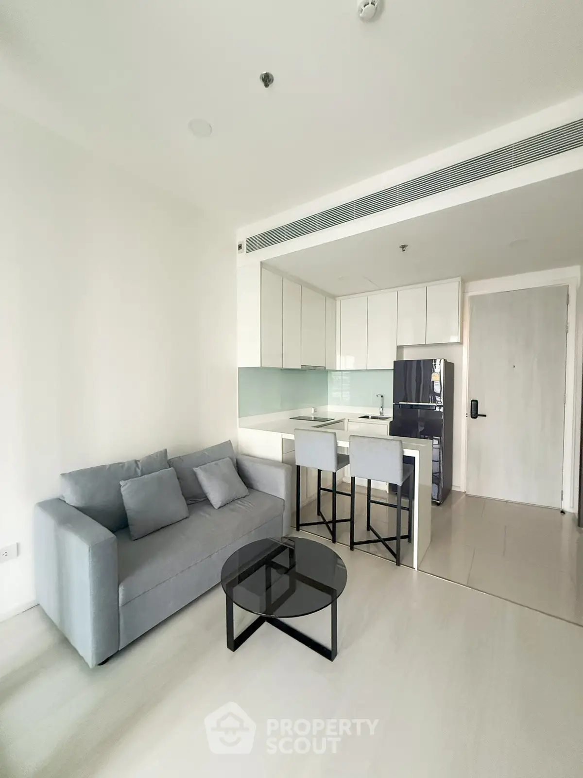Modern open-layout living room with sleek kitchen and stylish furniture in a contemporary apartment.