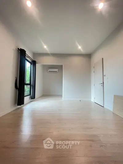 Spacious empty room with wooden flooring and large window