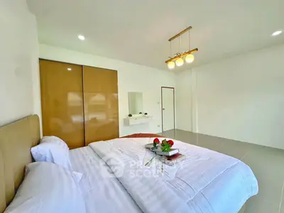 Spacious bedroom with modern decor and ample natural light, featuring a cozy bed and stylish lighting.
