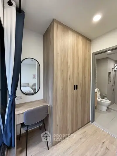 Modern bedroom with built-in wardrobe and study desk, adjacent to a sleek bathroom.
