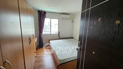 Cozy bedroom with city view, featuring wooden wardrobe and air conditioning.