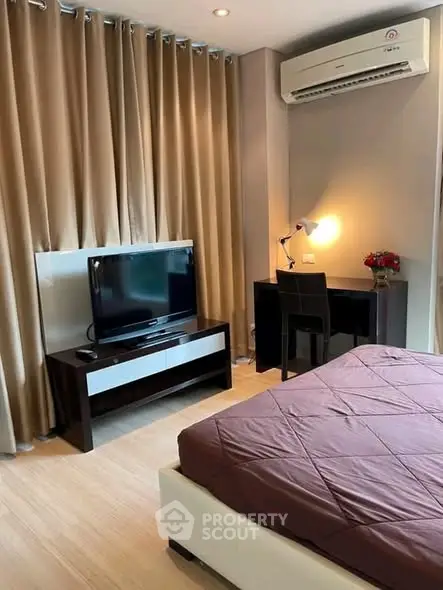 Cozy bedroom with TV, desk, and air conditioning, perfect for relaxation and work.
