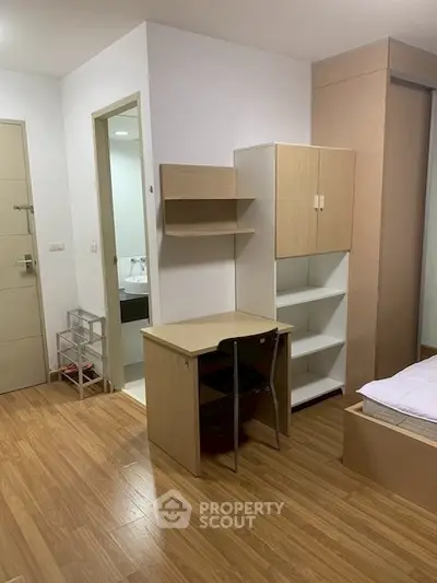 Modern bedroom with wooden flooring, study desk, and built-in storage in a cozy apartment.