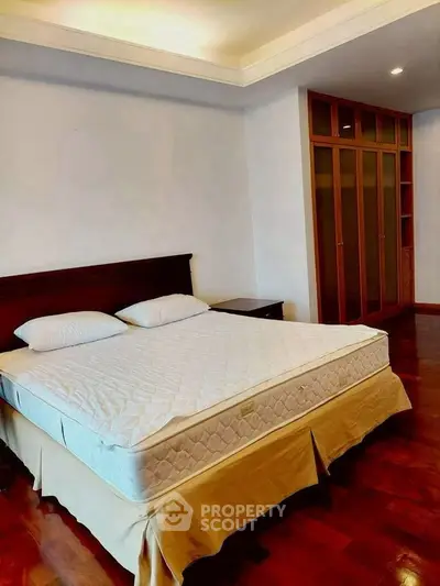 Spacious bedroom with elegant wooden flooring and built-in wardrobe