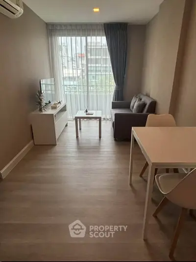 Modern living room with cozy sofa, TV, and dining area in a bright apartment.