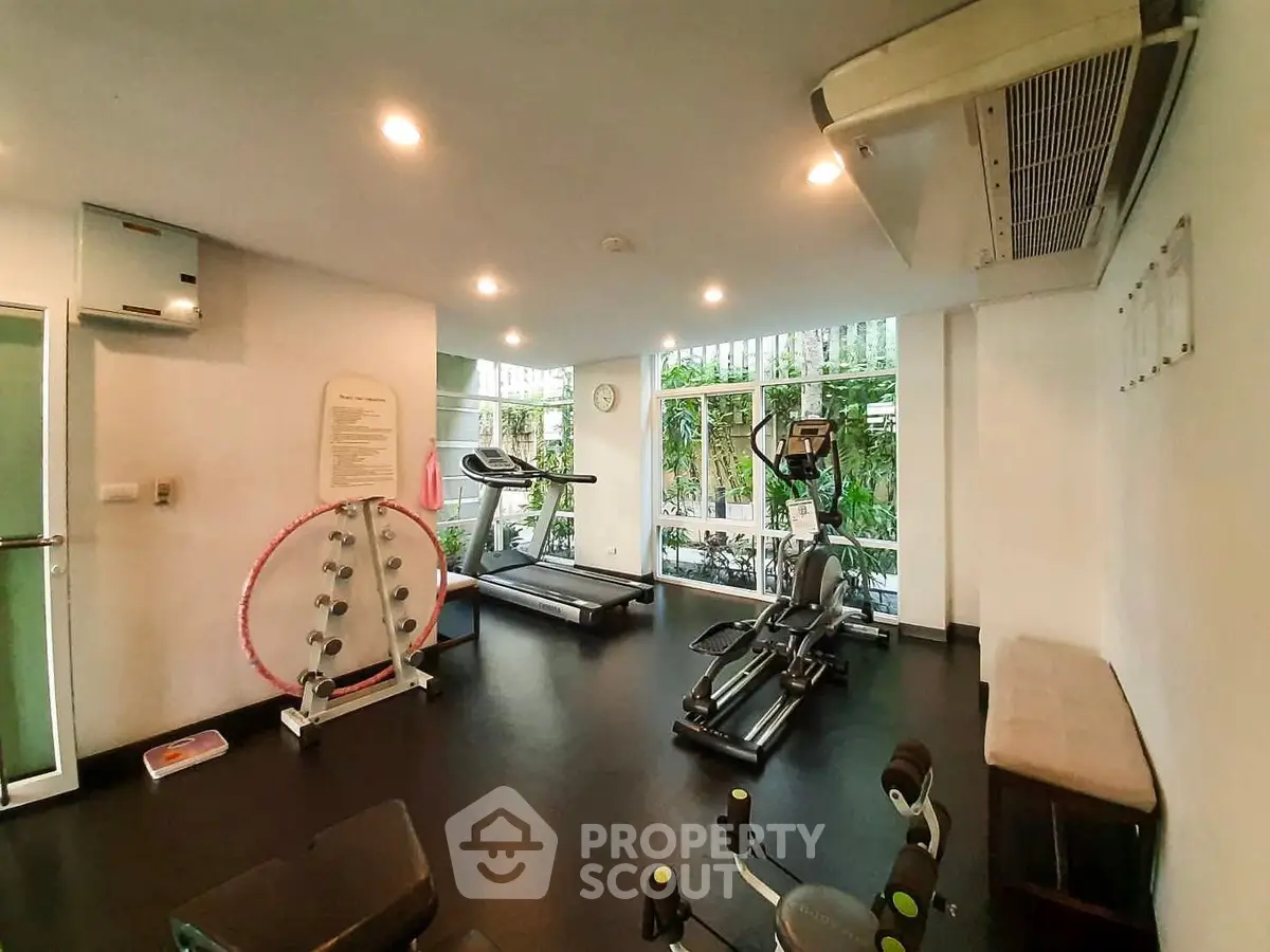 Modern gym with exercise equipment and large windows in a residential building.