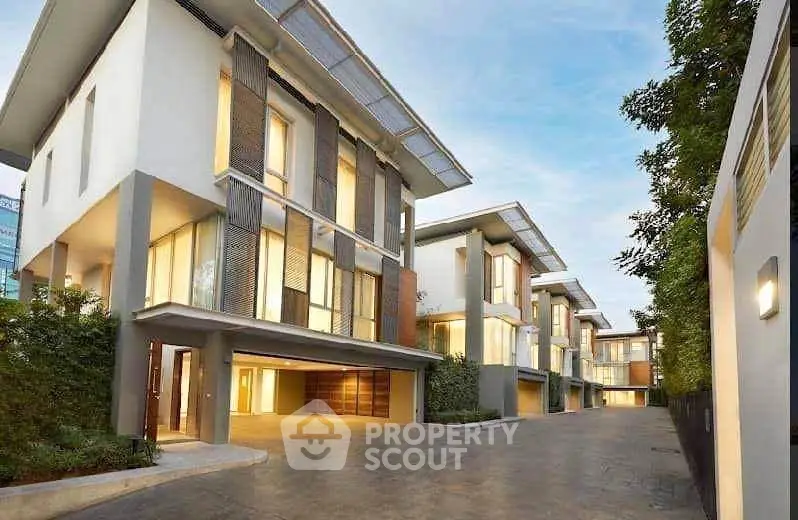 Luxurious modern townhouses with sleek design and spacious driveways in a serene neighborhood.