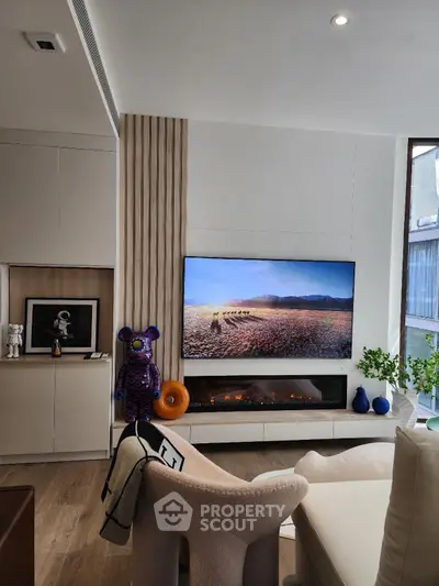 Modern living room with stylish decor, large TV, and cozy seating area.