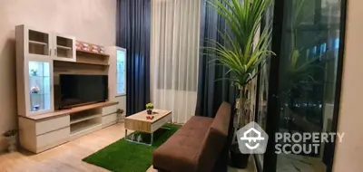 Cozy living room with modern furnishings, artificial grass accent, and access to a well-lit balcony, perfect for relaxation and entertainment.