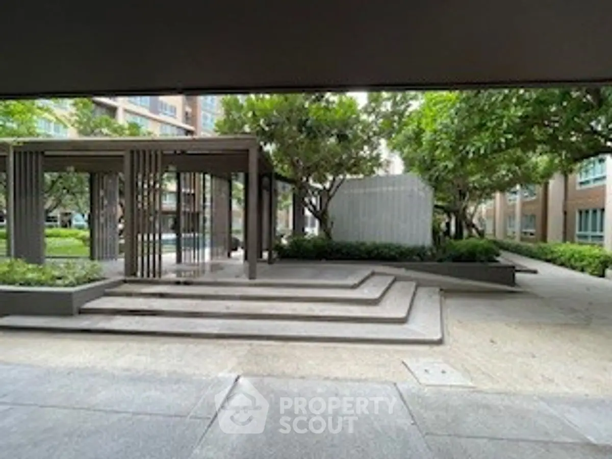 Modern apartment complex entrance with landscaped garden and stylish architecture.