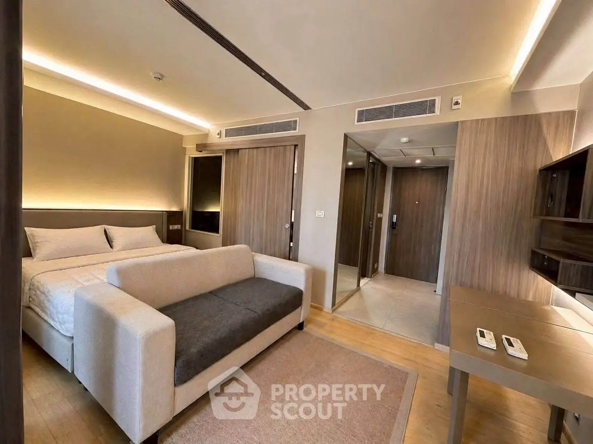 Modern bedroom with stylish decor and cozy seating area in a luxurious apartment.