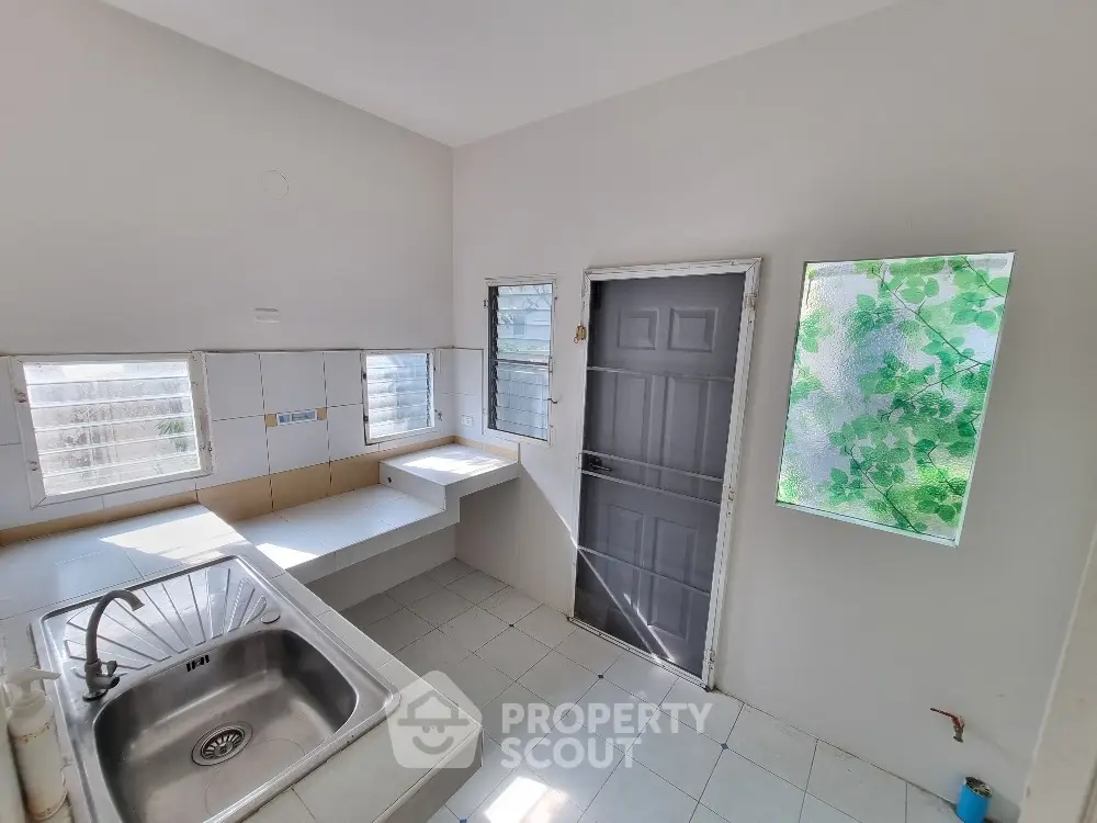 Bright kitchen with stainless steel sink and frosted window for privacy