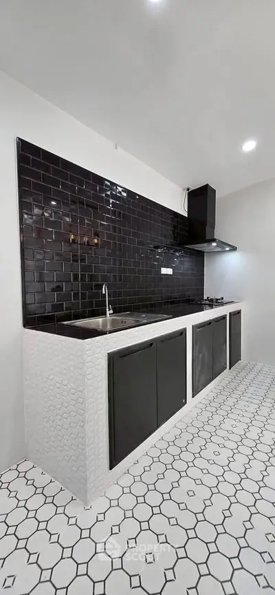 Modern kitchen with sleek black and white design, featuring a gas stove and stylish backsplash.