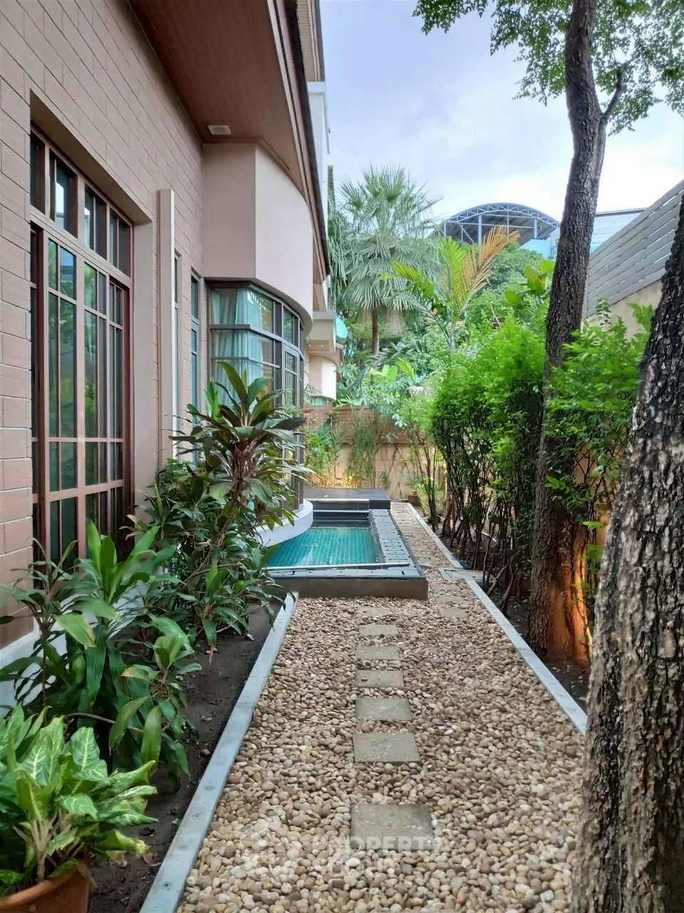 Charming garden pathway leading to a private pool in a serene residential setting.