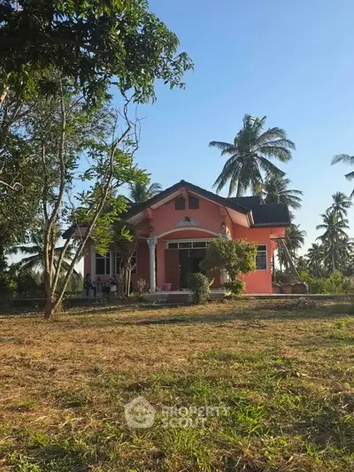 Charming pink house with lush palm trees and spacious garden, perfect for serene living.