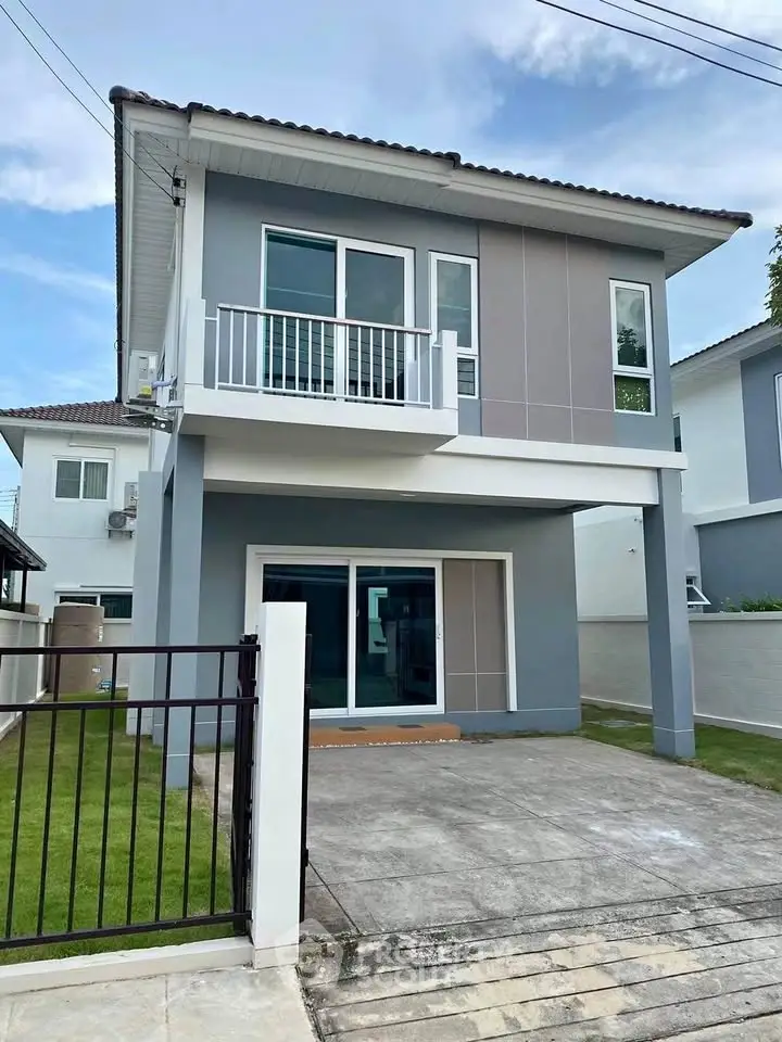 Modern two-story house with balcony and driveway in a suburban neighborhood.