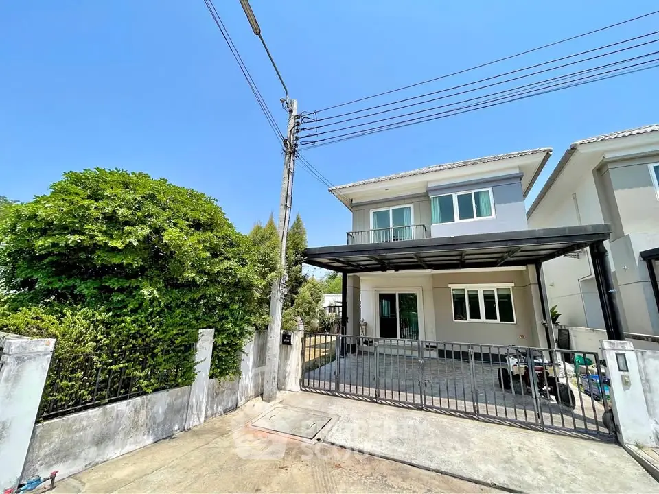 Modern two-story house with gated driveway and lush greenery, perfect for family living.
