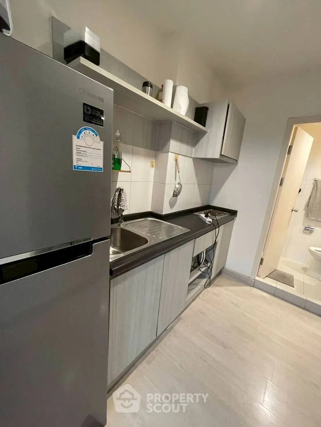 Modern kitchen with sleek cabinets and stainless steel fridge in a cozy apartment.