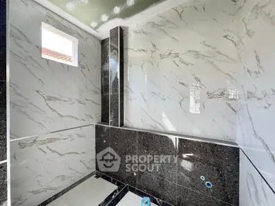 Luxurious marble-tiled bathroom under construction with natural light