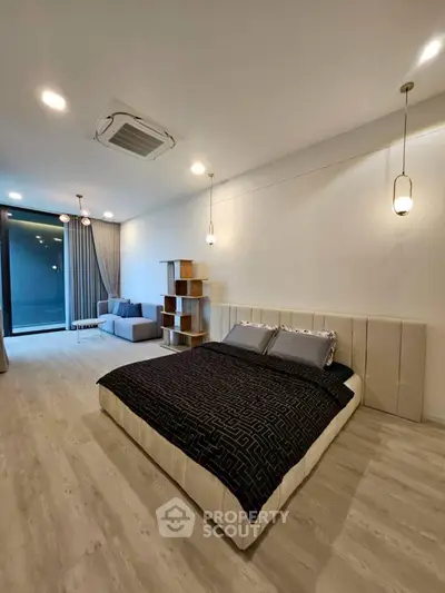 Spacious modern bedroom with elegant lighting and cozy seating area