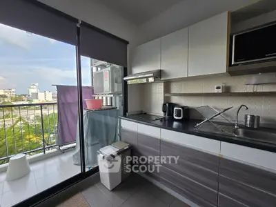 Modern kitchen with balcony view, featuring sleek cabinets and appliances.