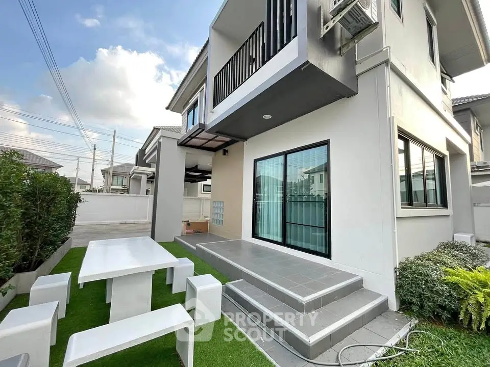 Modern two-story house with outdoor seating and lush greenery