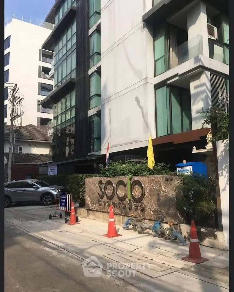 Modern condominium building exterior with stylish facade and entrance signage in urban setting.