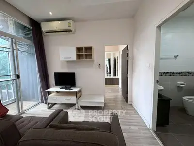 Modern living room with balcony access and adjacent bathroom in stylish apartment.