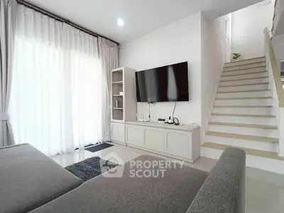 Modern living room with sleek design, large TV, and elegant staircase, perfect for contemporary living.