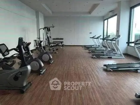 Spacious modern gym with state-of-the-art fitness equipment and large windows for natural light.