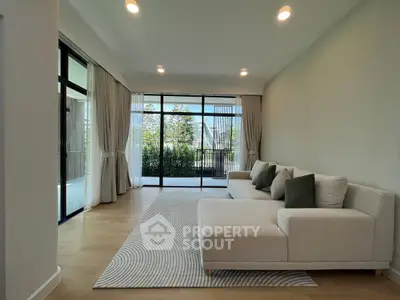 Spacious living room with modern decor and large windows offering garden views.