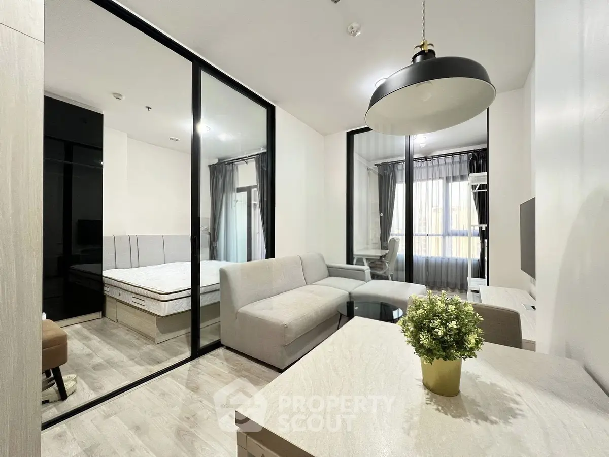 Modern studio apartment with glass partition, cozy living area, and stylish decor.