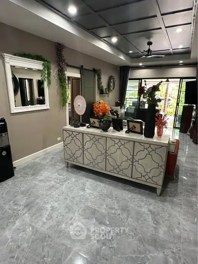 Elegant living room with modern decor and large windows opening to a balcony, featuring stylish furniture and marble flooring.