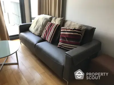 Modern living room with stylish leather sofa and striped cushions near a glass coffee table.