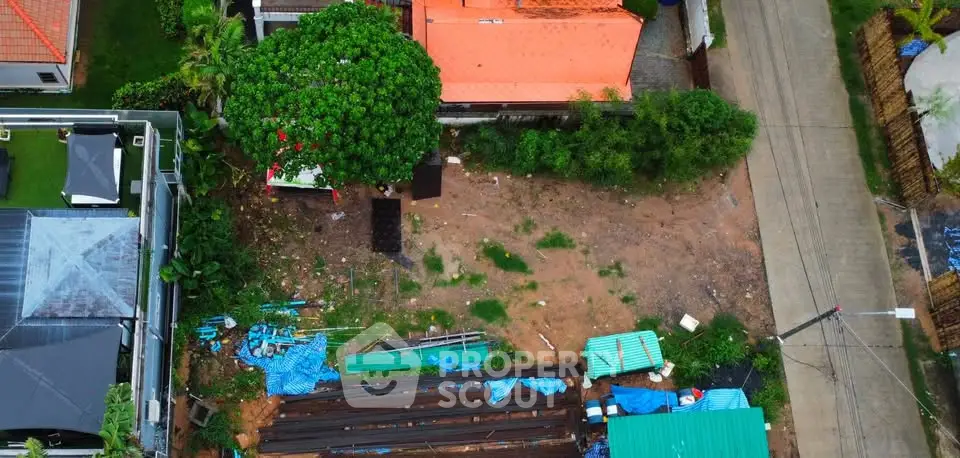Aerial view of a residential plot with construction materials and greenery, ideal for development.