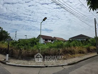 Vacant land plot with lush greenery and residential backdrop