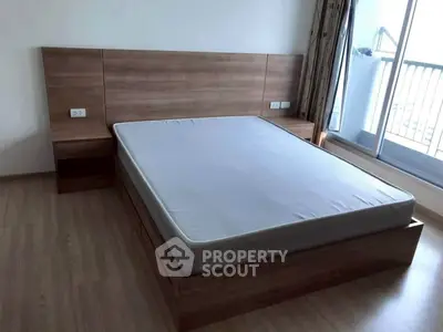 Spacious bedroom with modern wooden bed frame and balcony access, perfect for relaxation and comfort.
