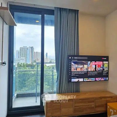 Modern living room with balcony view and wall-mounted TV in urban apartment.