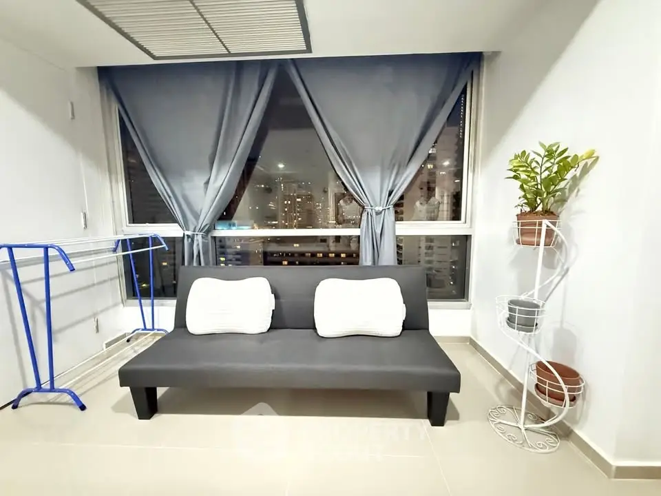 Modern living room with city view, featuring a sleek black sofa and stylish decor.