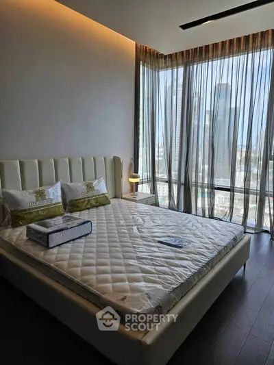 Luxurious bedroom with floor-to-ceiling windows offering stunning city views and elegant decor.