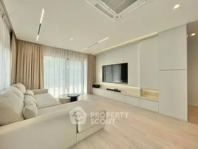 Modern living room with sleek design, large sofa, and wall-mounted TV, featuring natural light and elegant curtains.